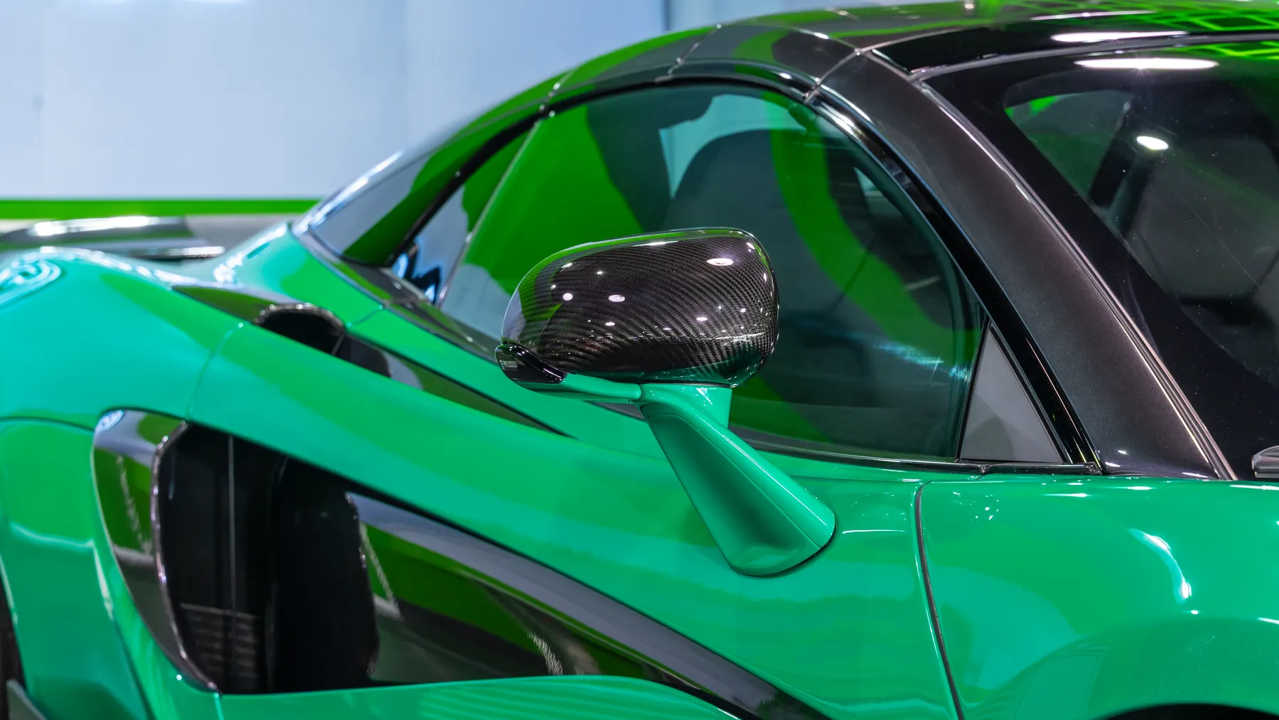 Close detail of a carbon-fibre wing mirror on a green sports car