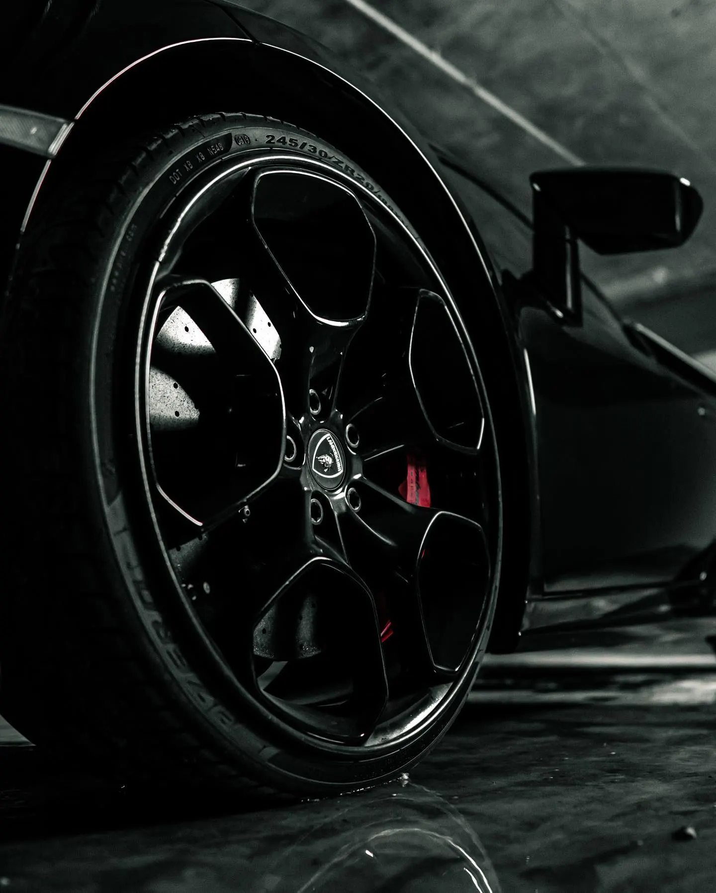 Close detail of the rear wheel and brake caliper of a dark sports car