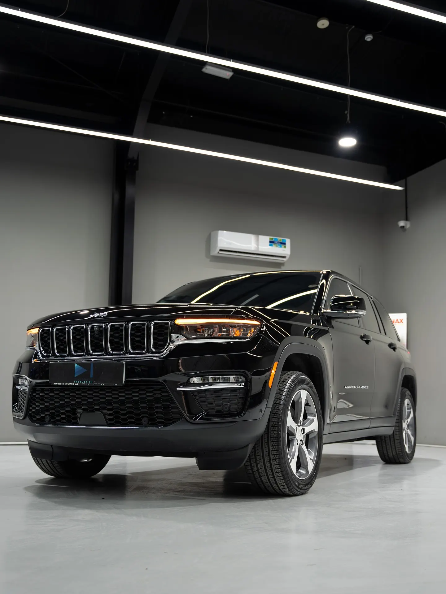 A black SUV photographed head-on under indoor lighting, grille and headlamps lit