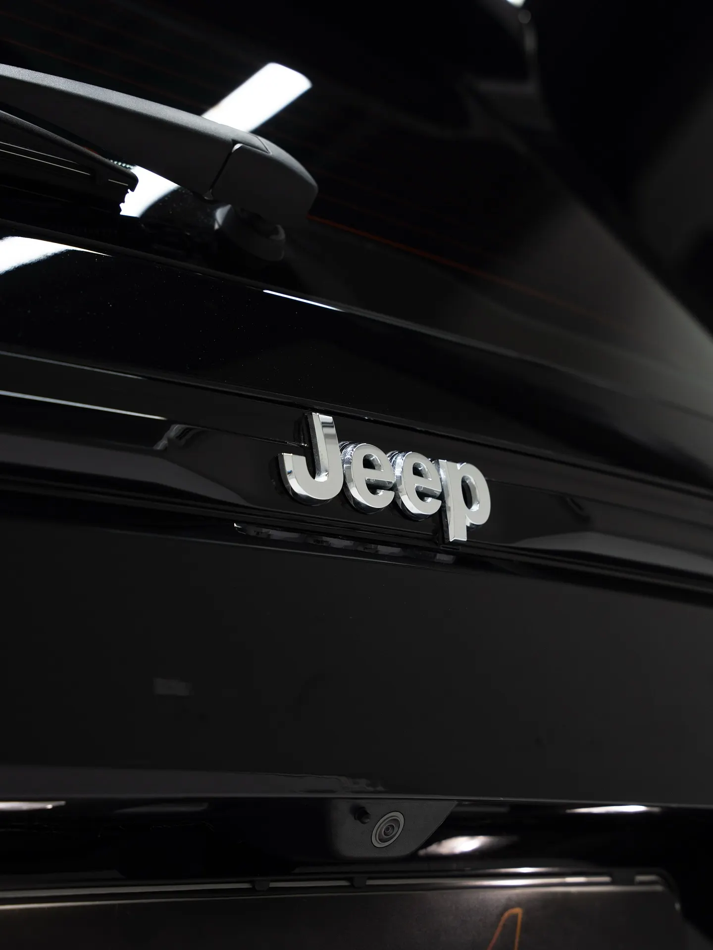 The rear tailgate and badge of a black SUV under showroom lighting