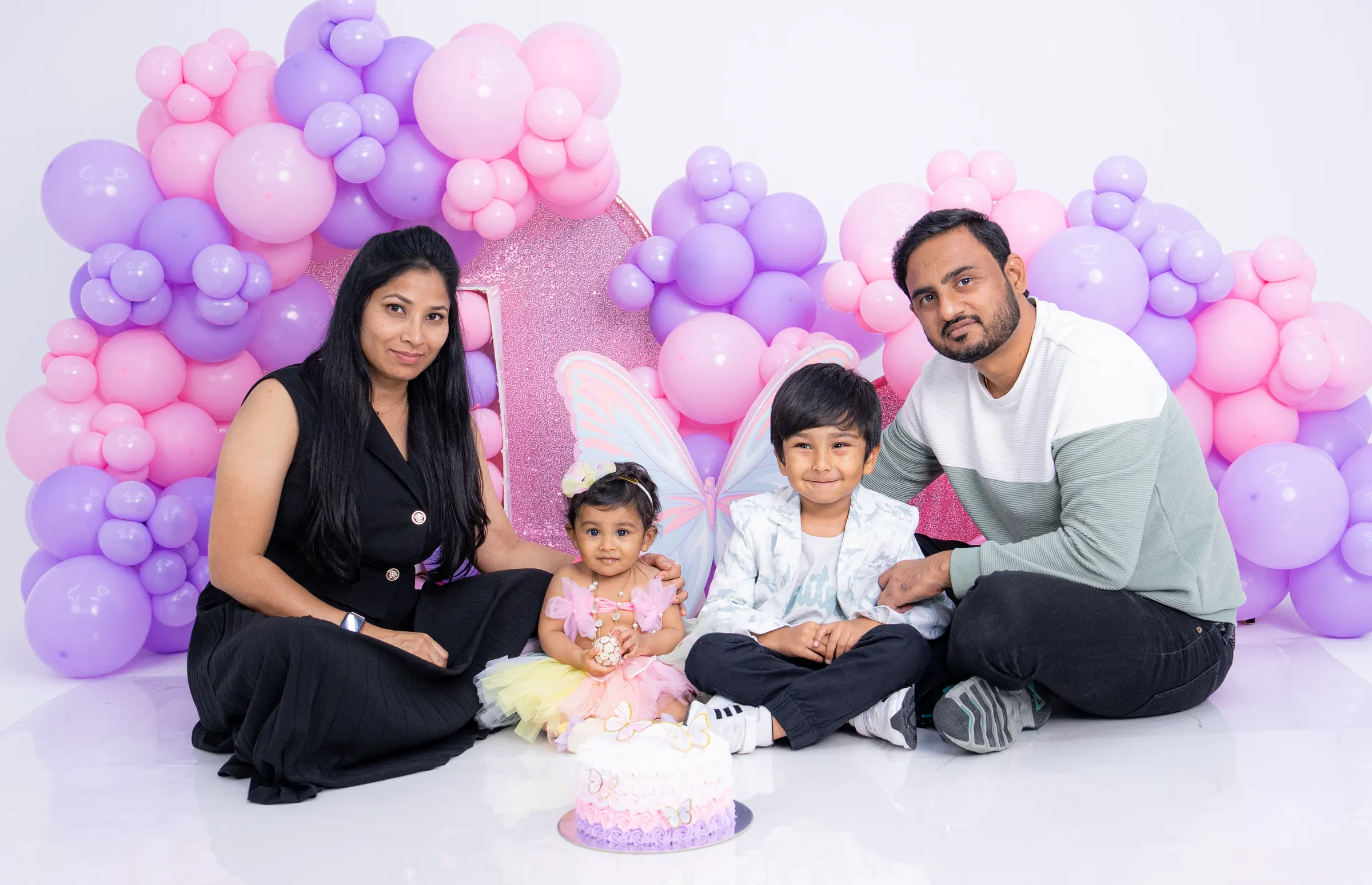 Family posing at a pink balloon birthday party setup