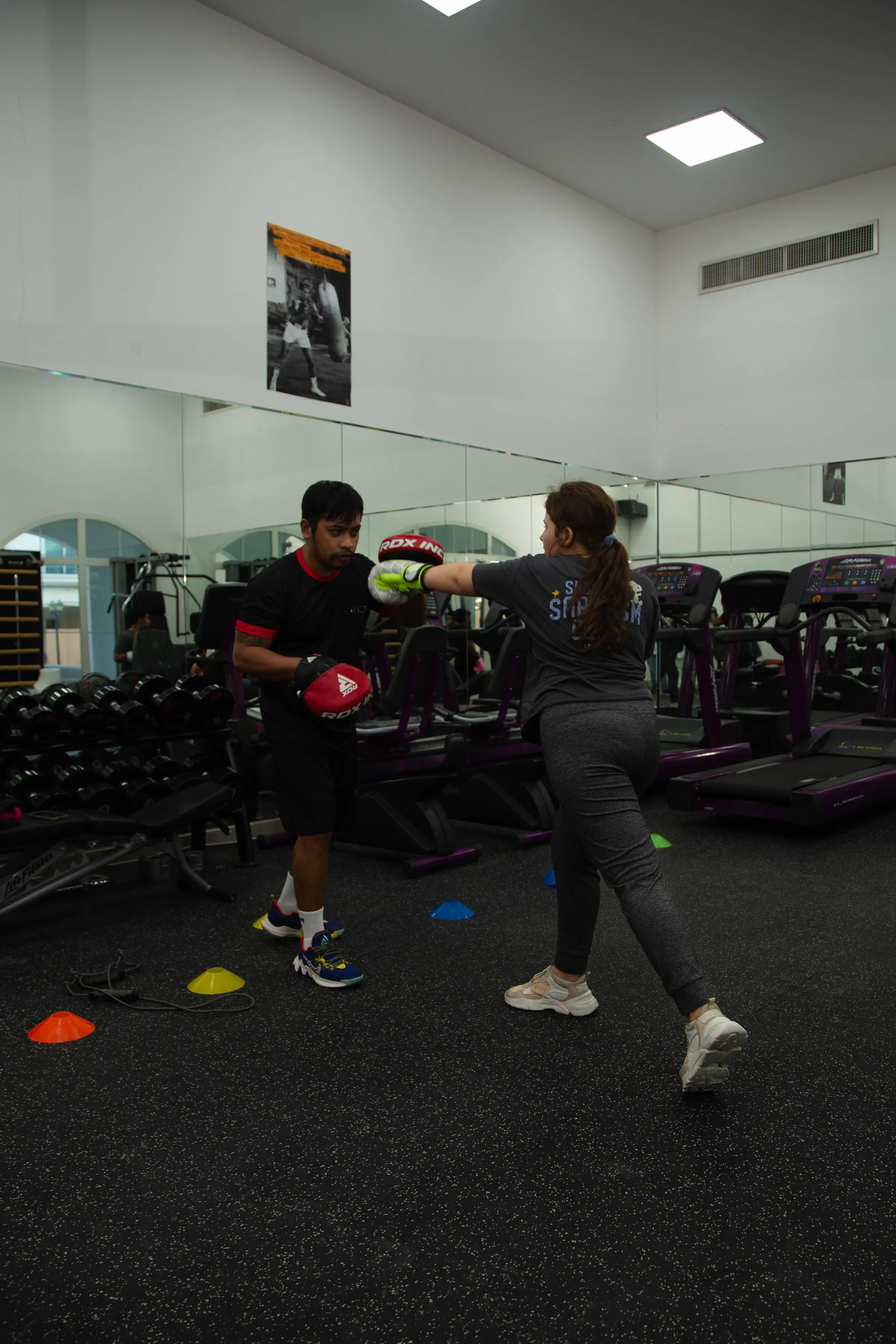 Two people training with boxing pads in a gym