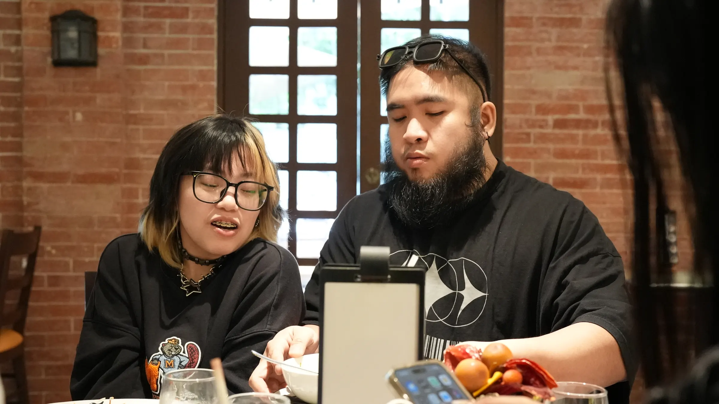 Two people seated at a table in a cafe with exposed brick walls