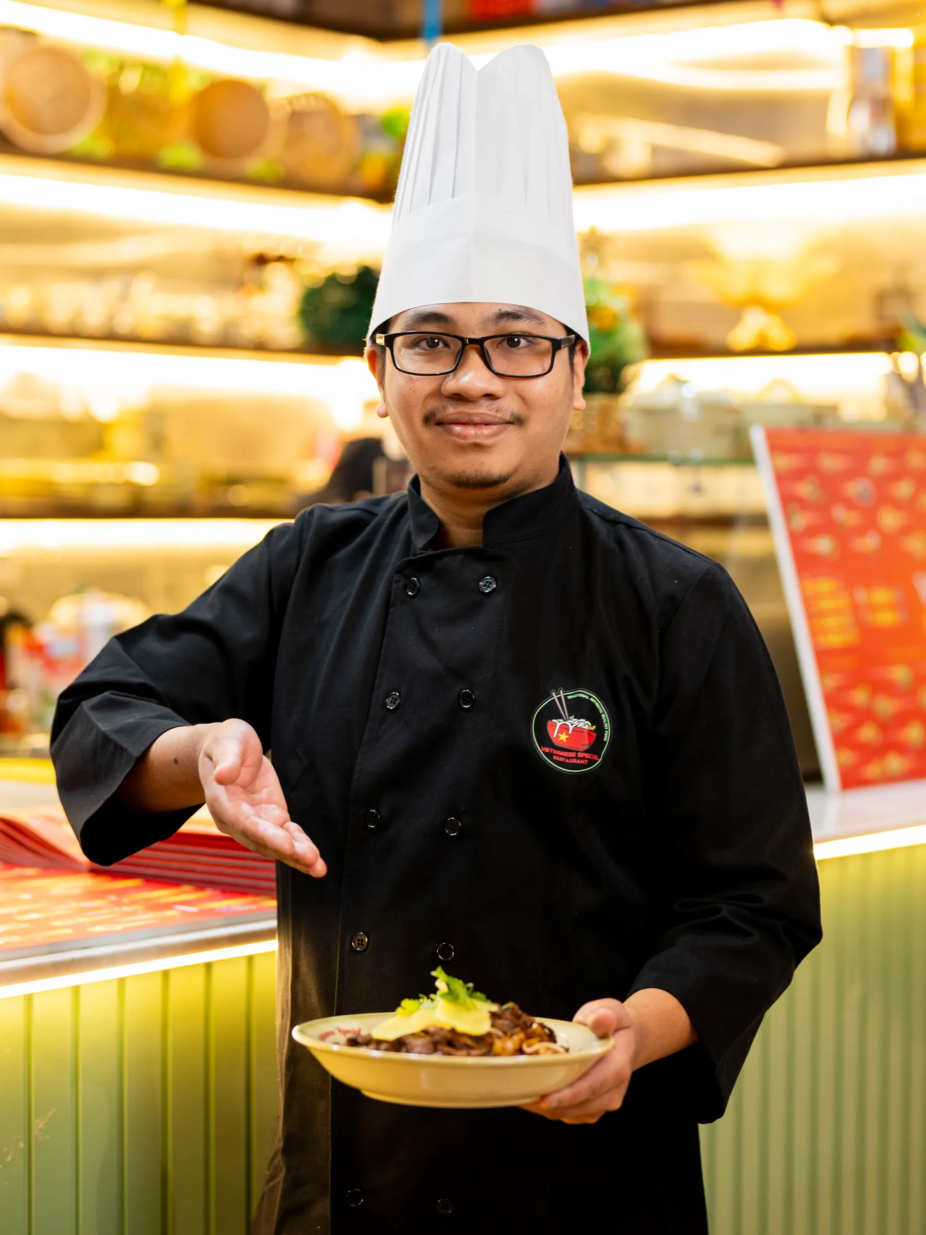 Chef in whites presenting a plated dish in a restaurant