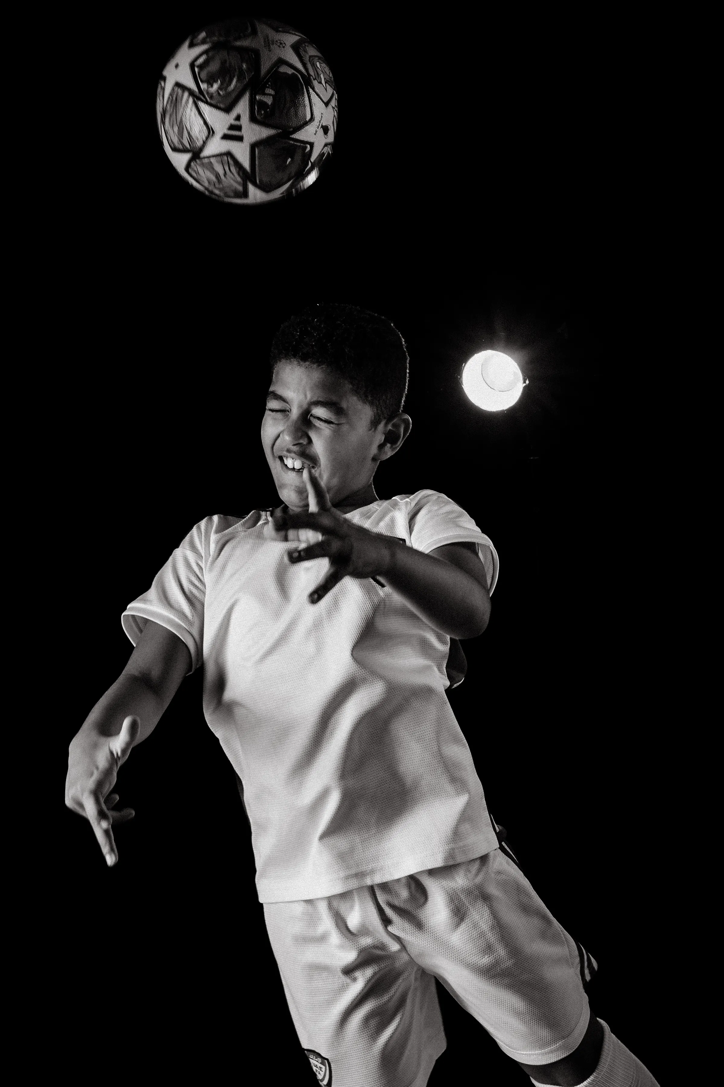 Black and white composite of a boy striking a football