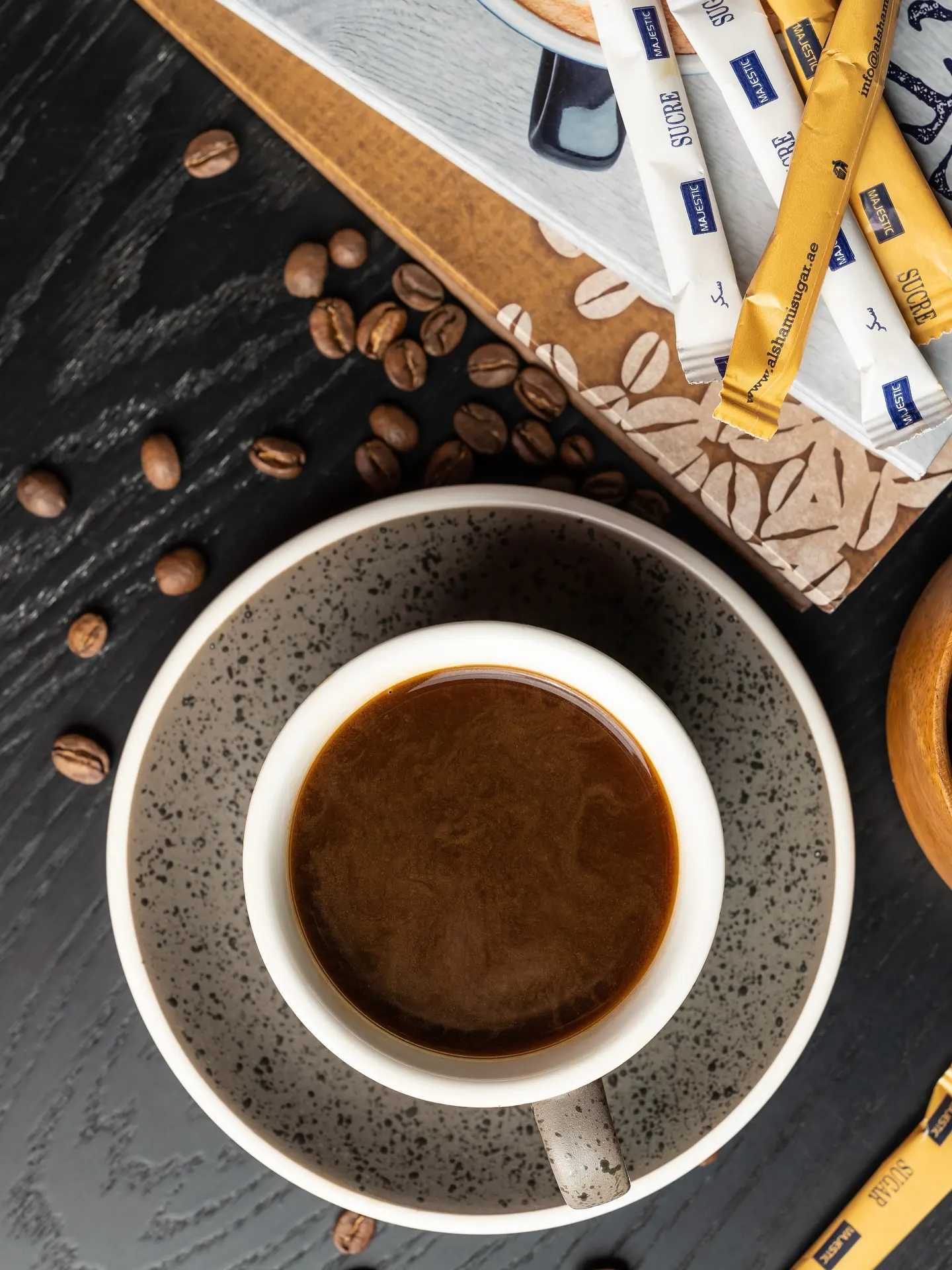 A cup of Turkish coffee on a dark surface, scattered coffee beans and pencils around it