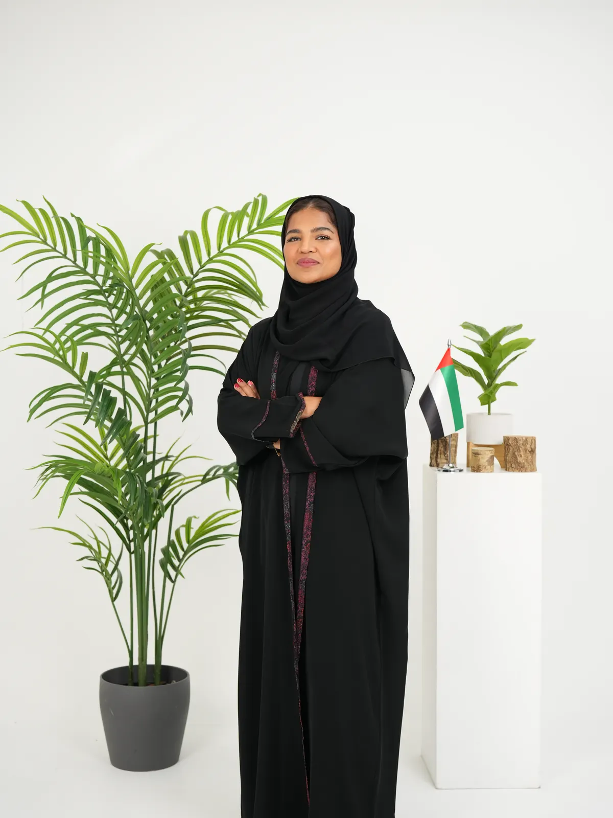 Standing corporate portrait of a woman in an abaya against a white backdrop