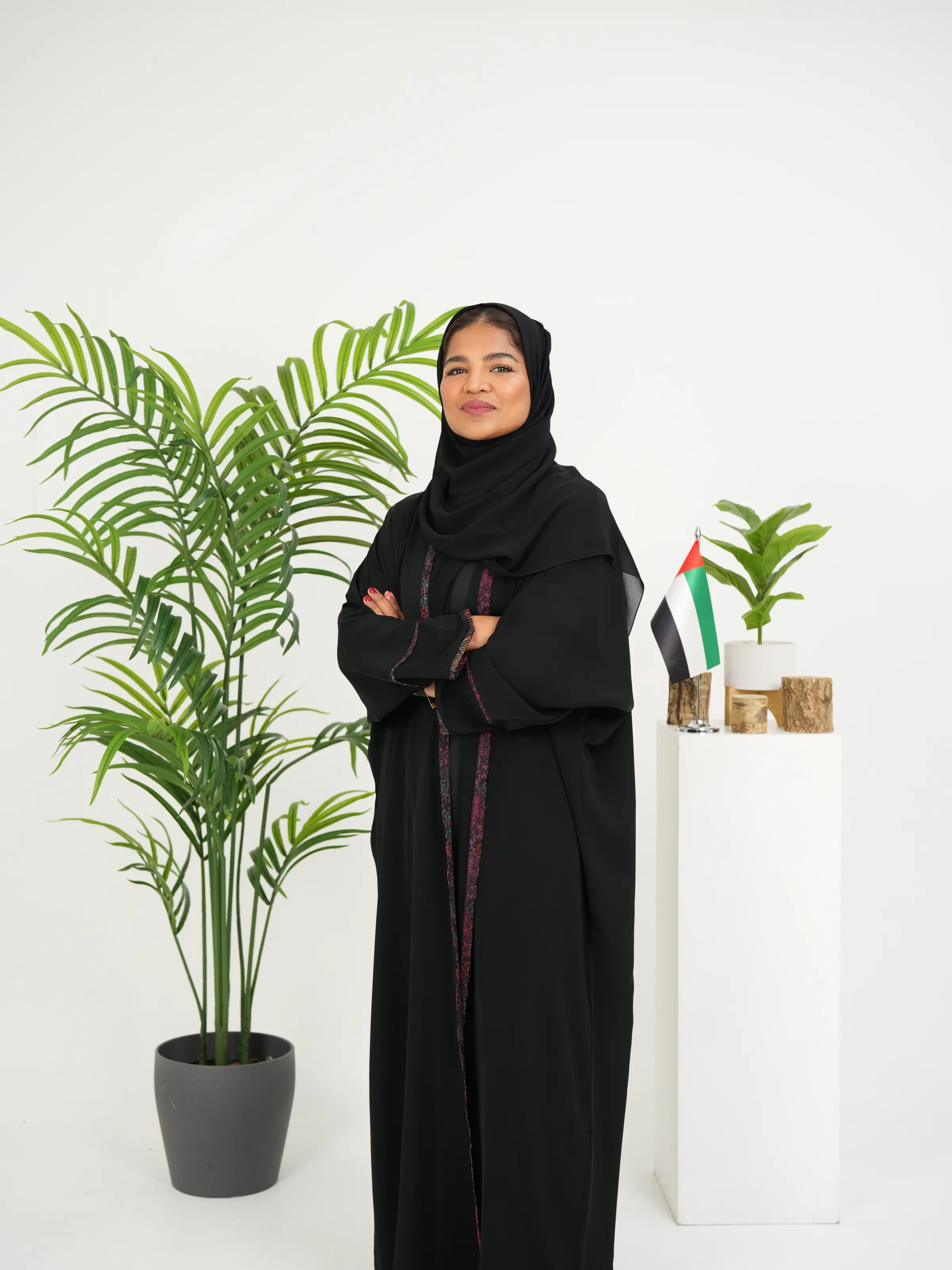 Standing corporate portrait of a woman in an abaya against a white backdrop