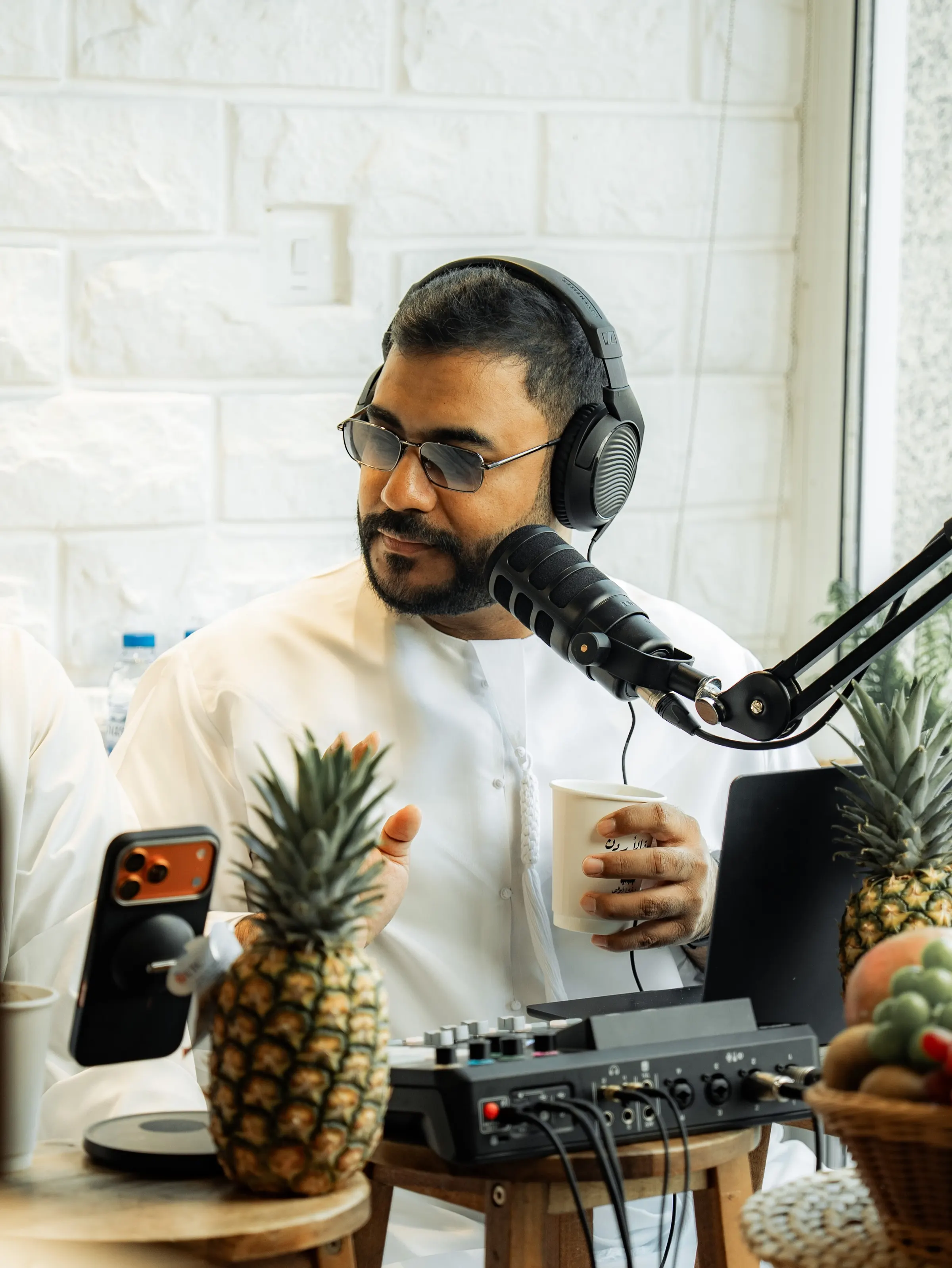 Podcast host at a microphone beside a pineapple on the desk