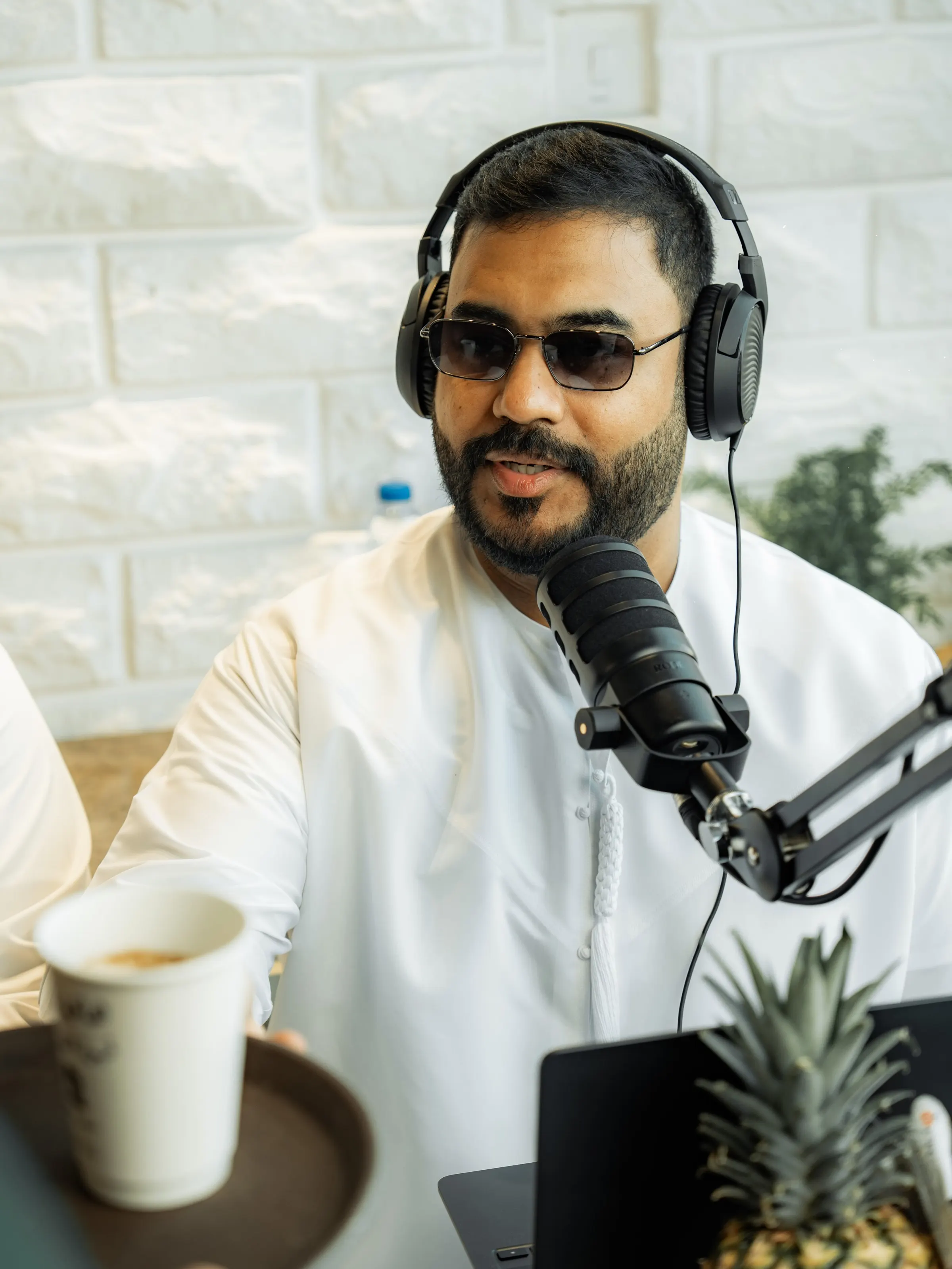 Podcast host in sunglasses at a microphone