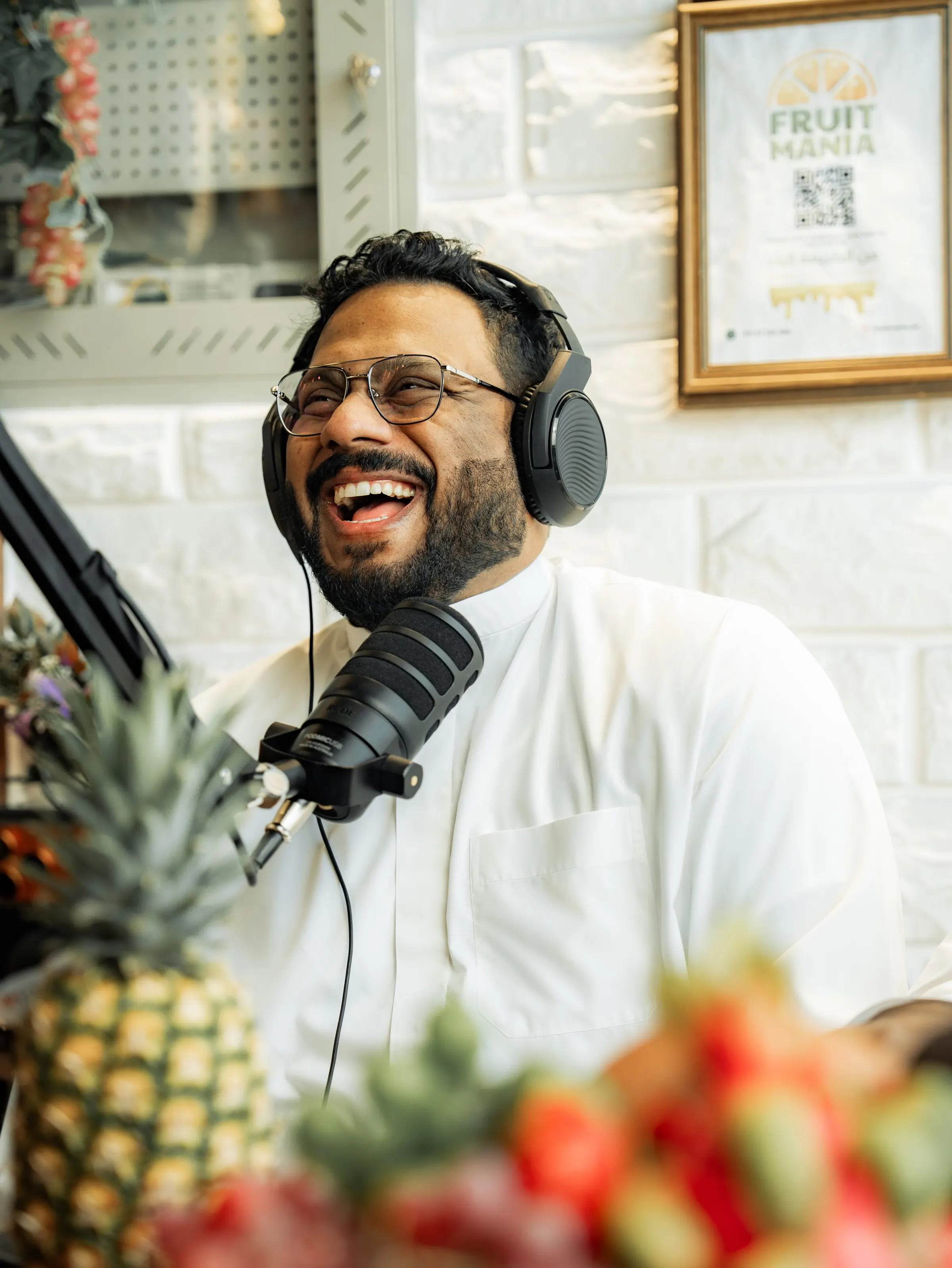 Two podcast hosts laughing at a set dressed with fresh fruit