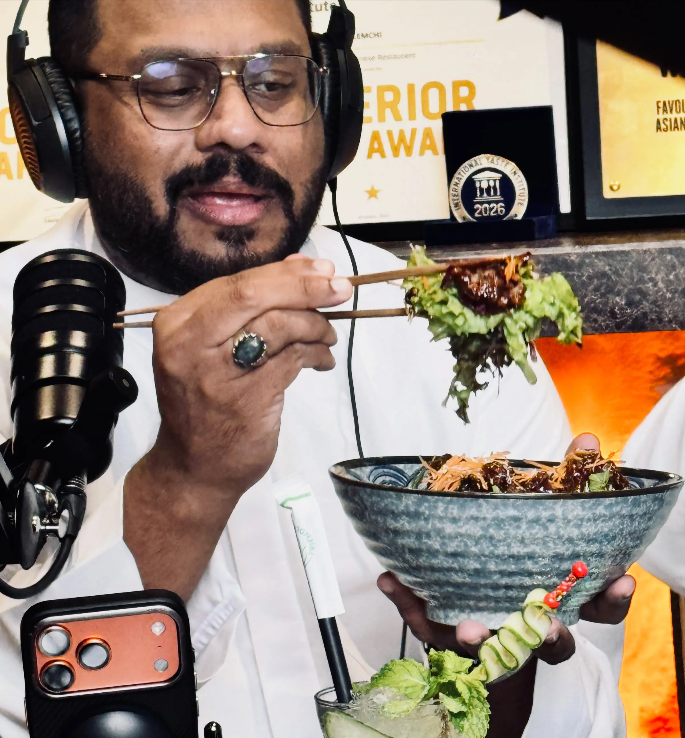 Podcast host lifting food from a bowl at a restaurant microphone