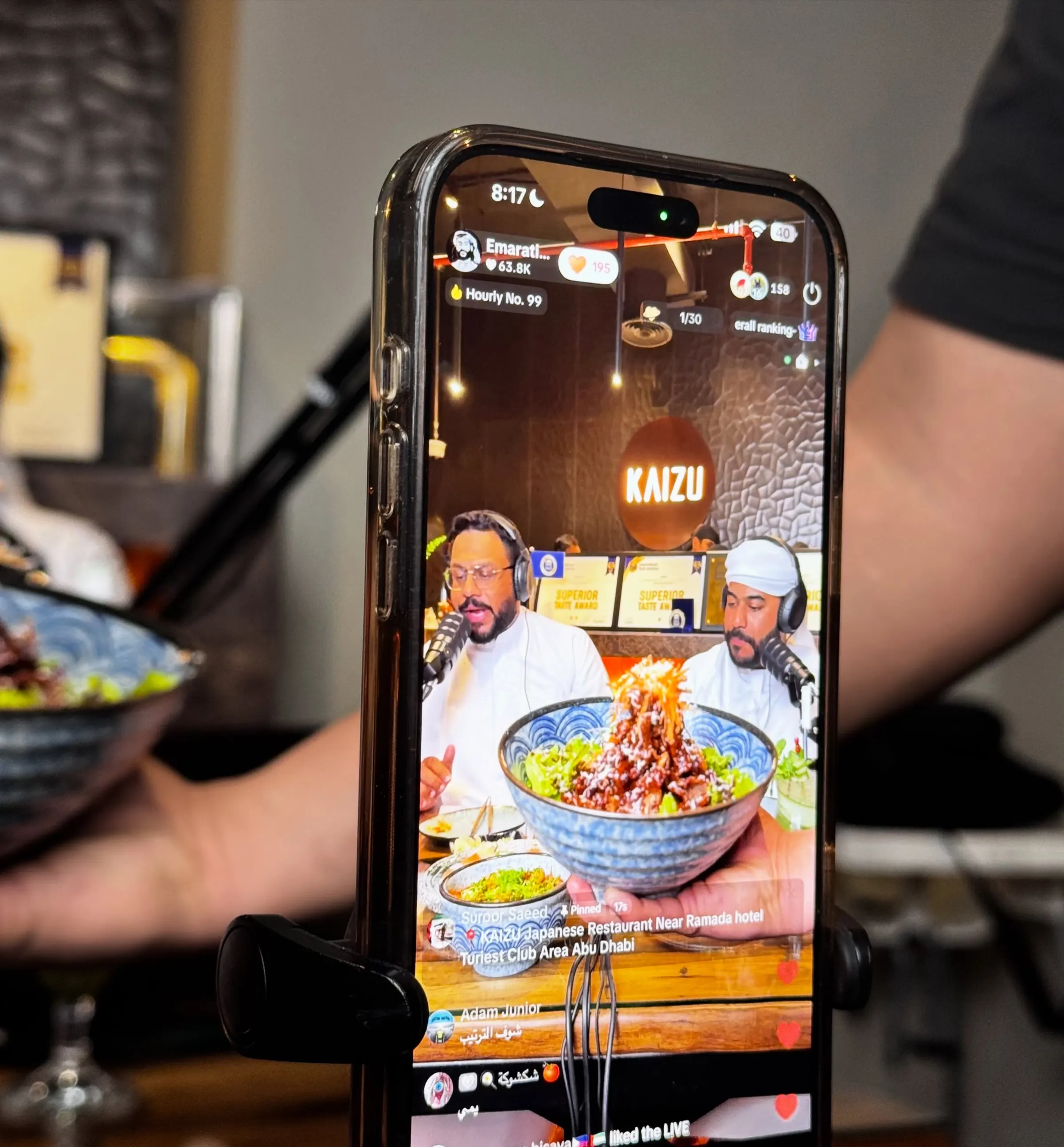 A phone filming a restaurant podcast as a live stream