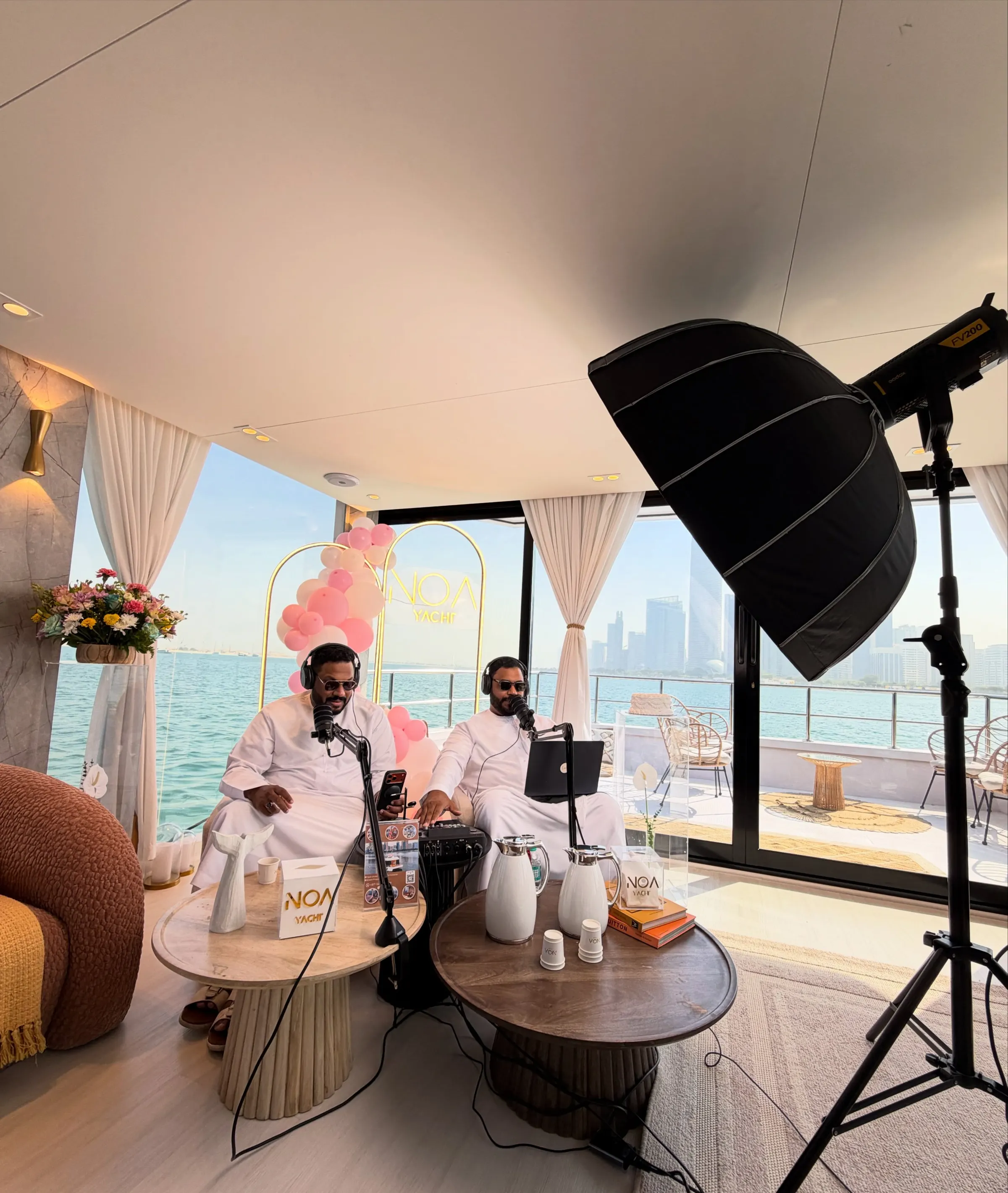 A podcast set rigged on a yacht deck: softbox, chairs and a low table