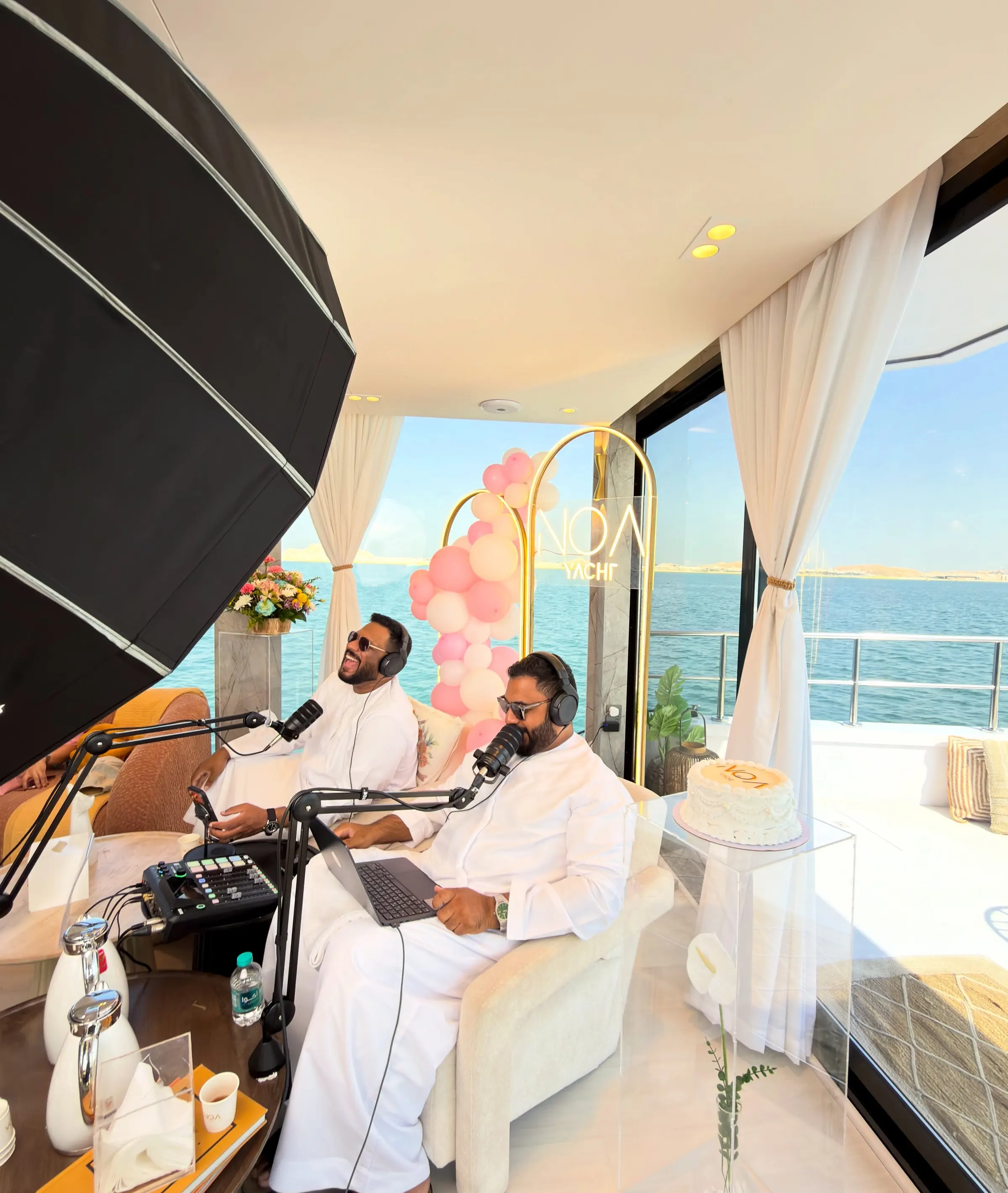 Two podcast hosts recording aboard a yacht, sea through the window