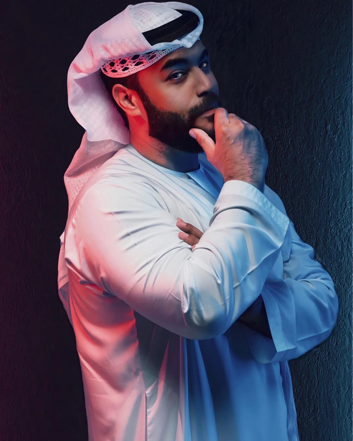 Studio portrait of a man in traditional Emirati dress lit with coloured gels