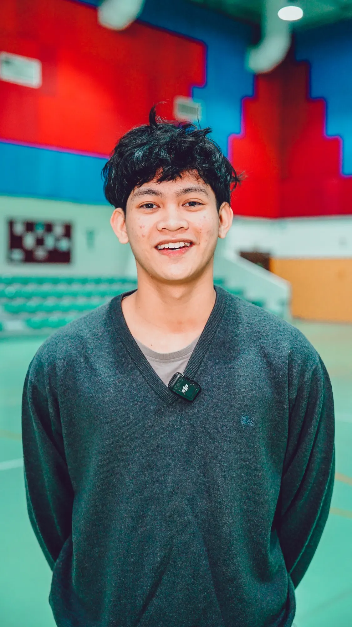 Alijah Paul Palao Javelona smiling in a dark grey sweater in a sports hall