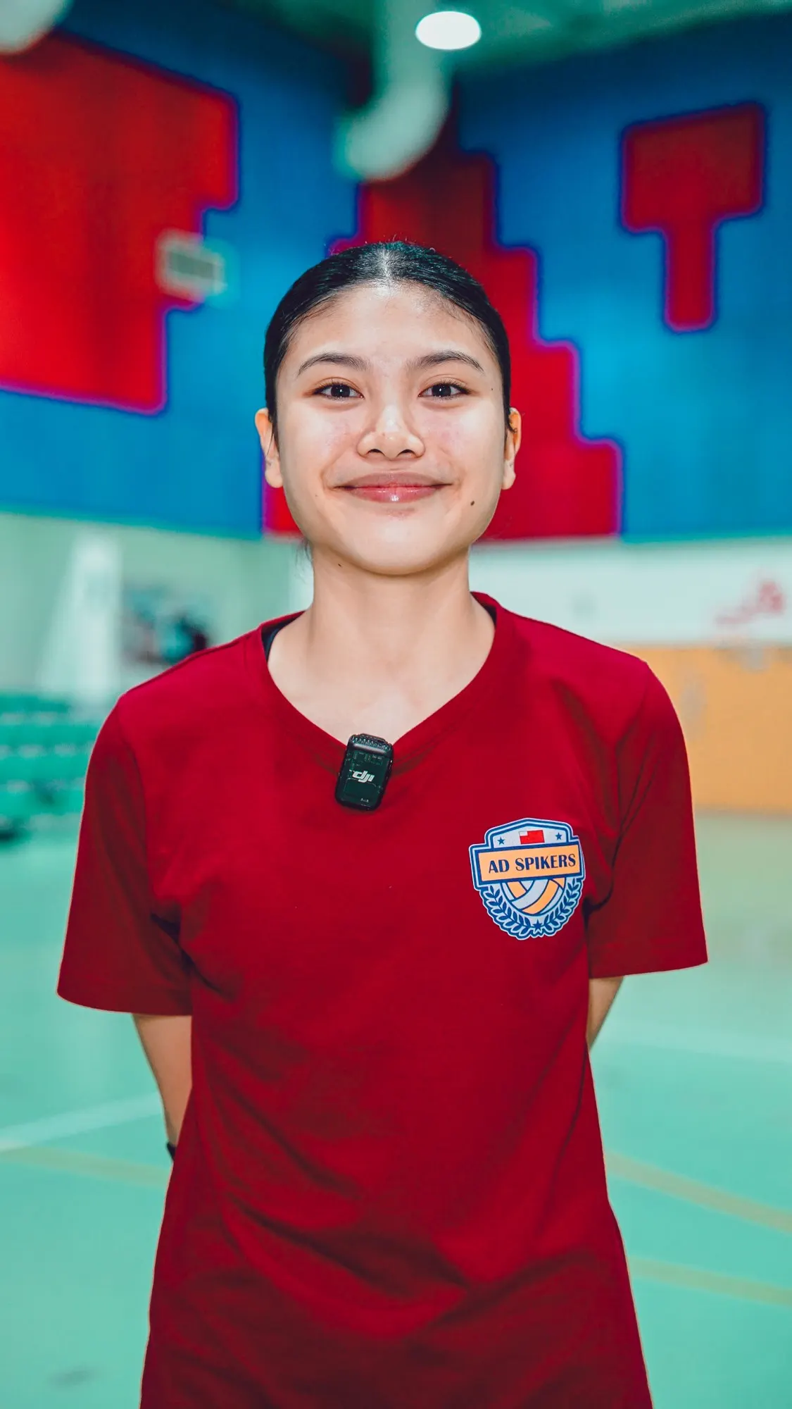 Jamila Angela Mendoza Santander smiling in a red AD Spikers shirt in a sports hall