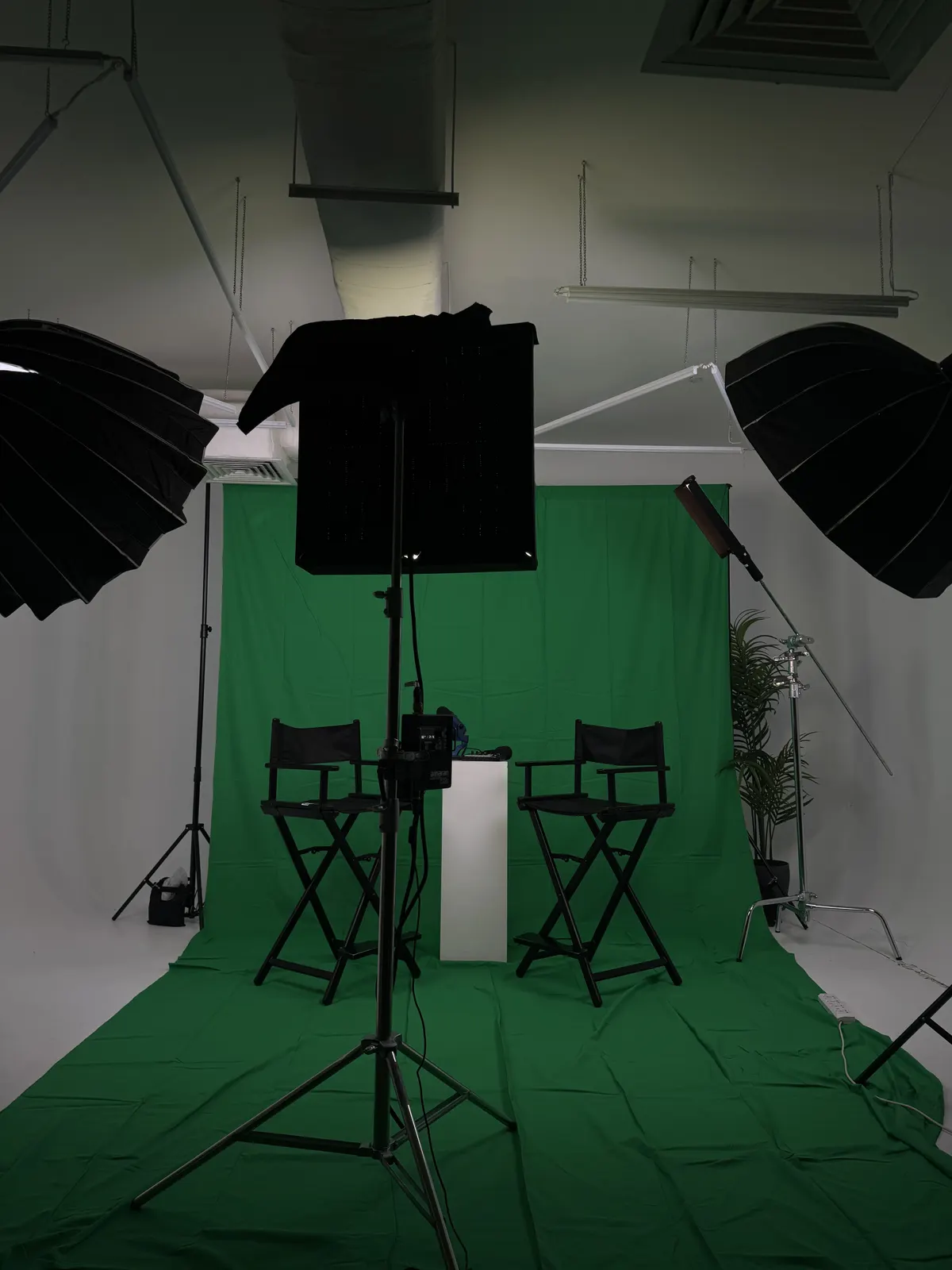 Green screen studio set with two director's chairs and studio lighting
