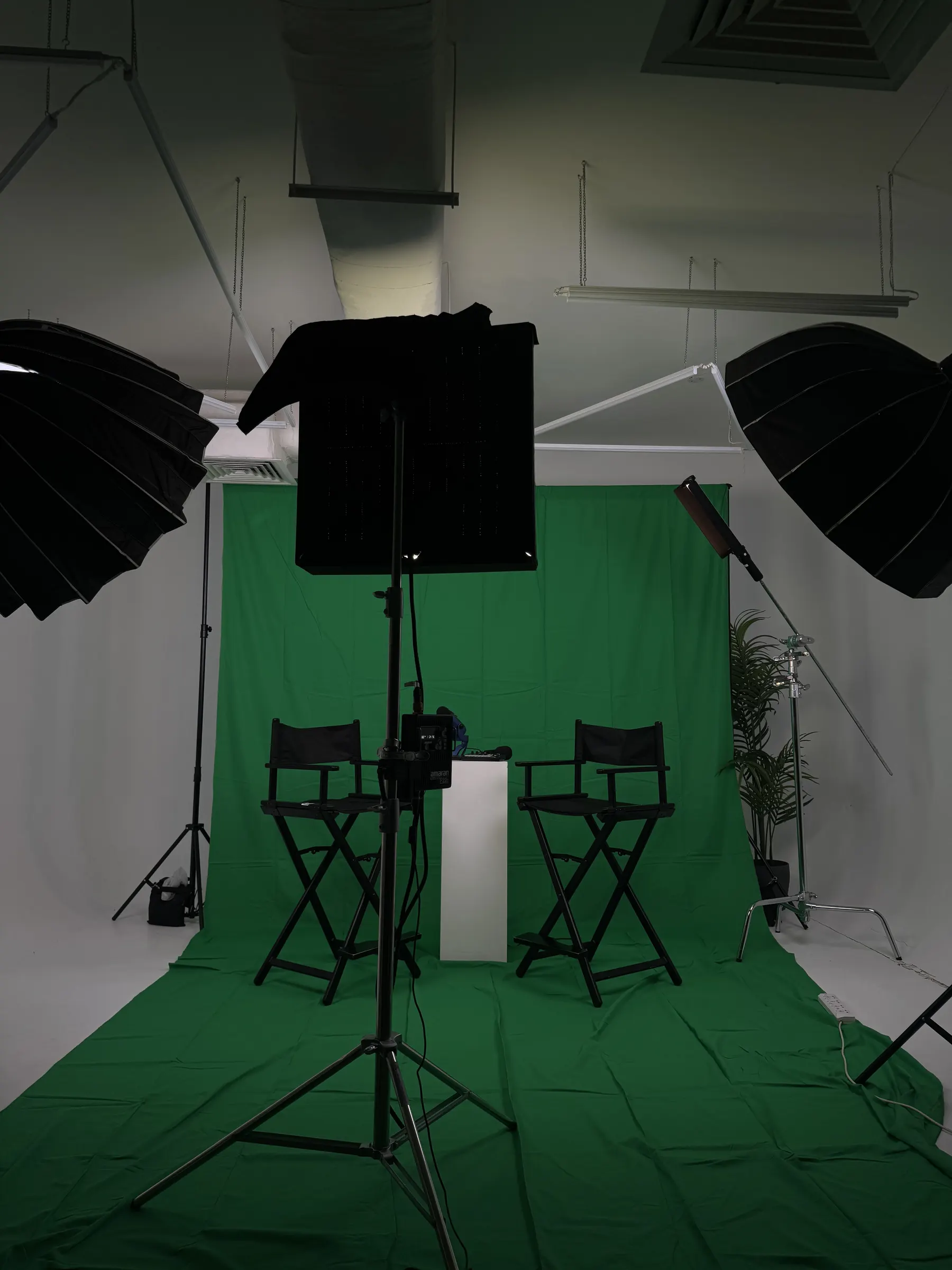 Green screen studio set with two director's chairs and studio lighting