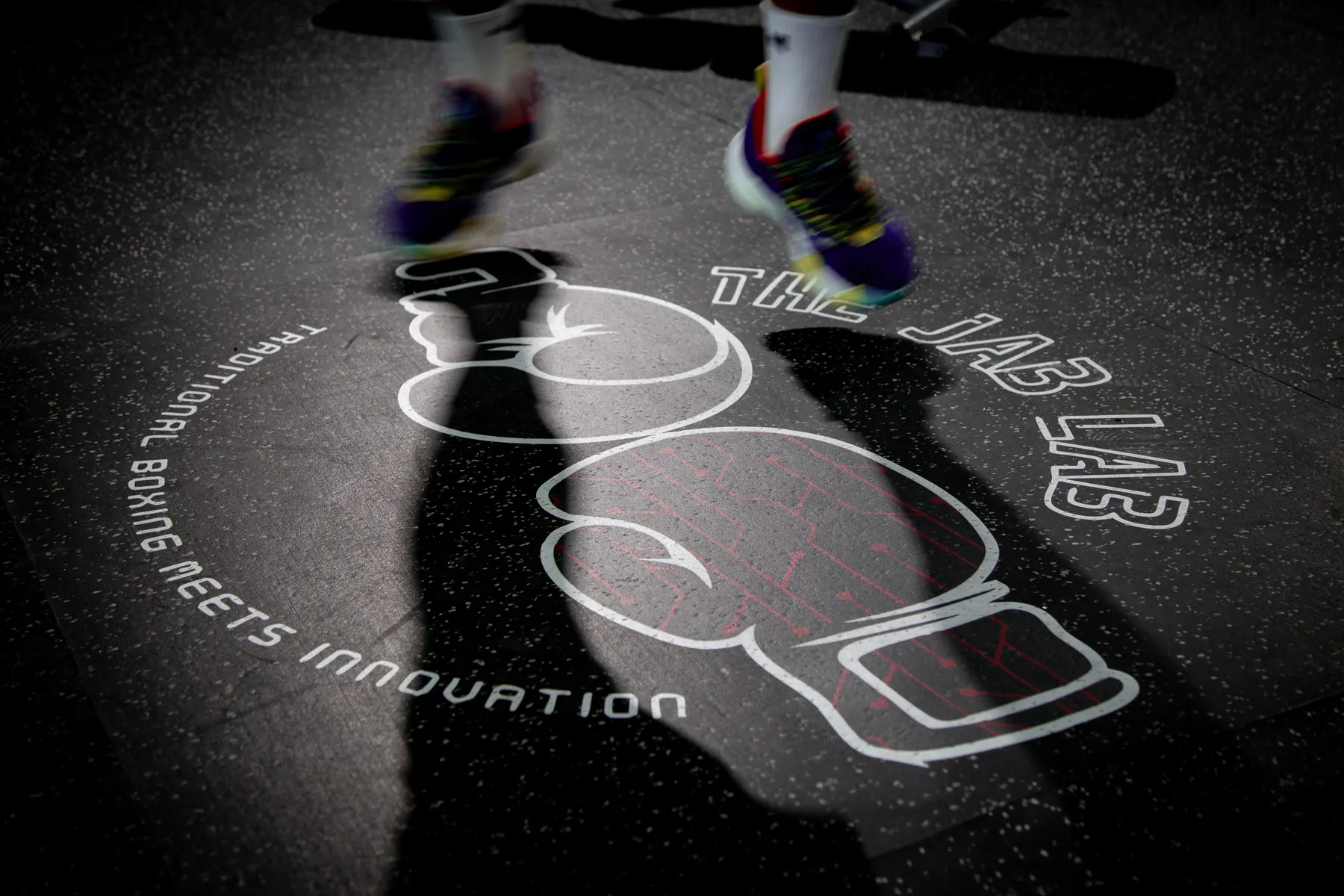 Light projection of boxing gloves and a club wordmark cast across a gym floor