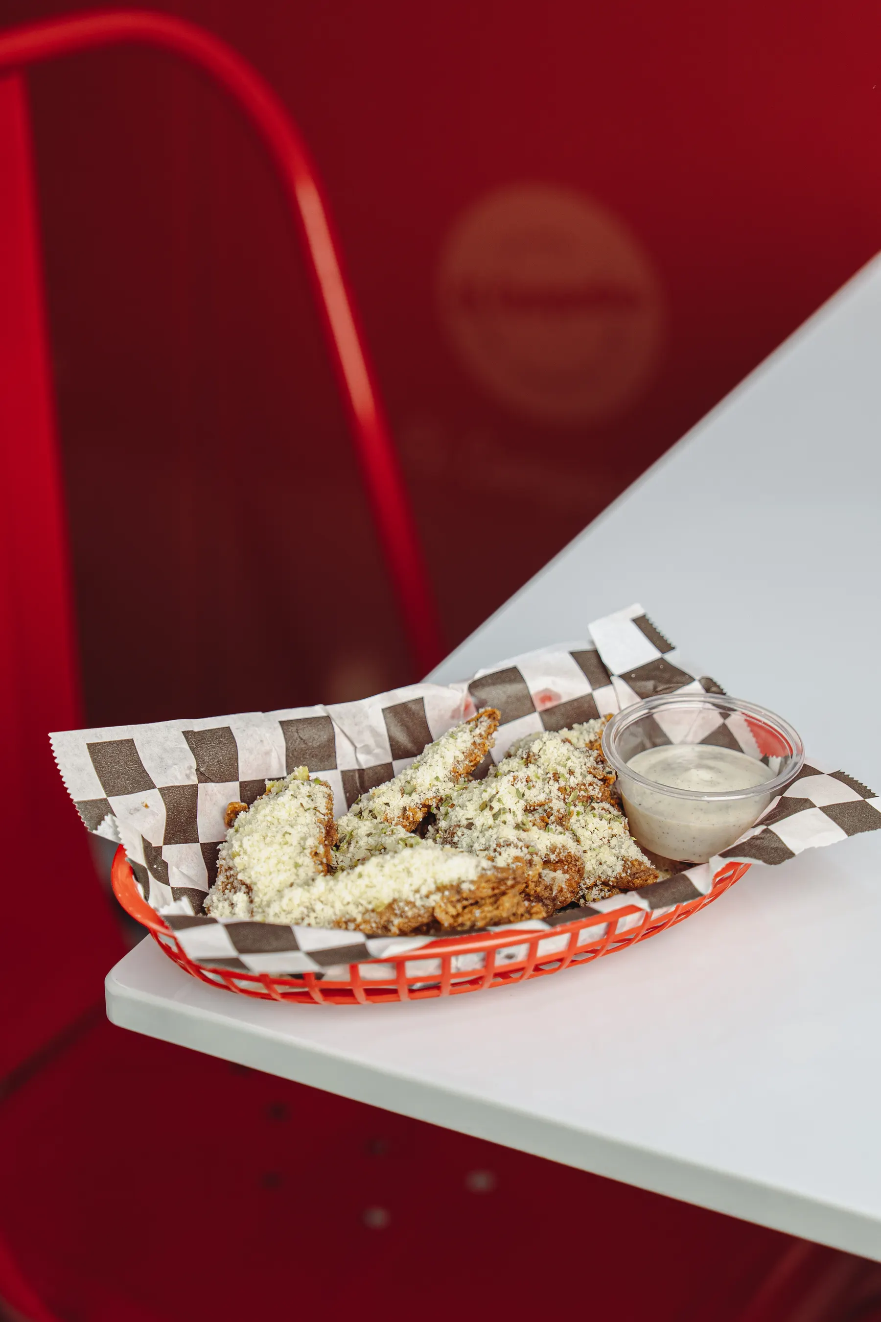 Basket of fried snacks with dip on a red and white studio set