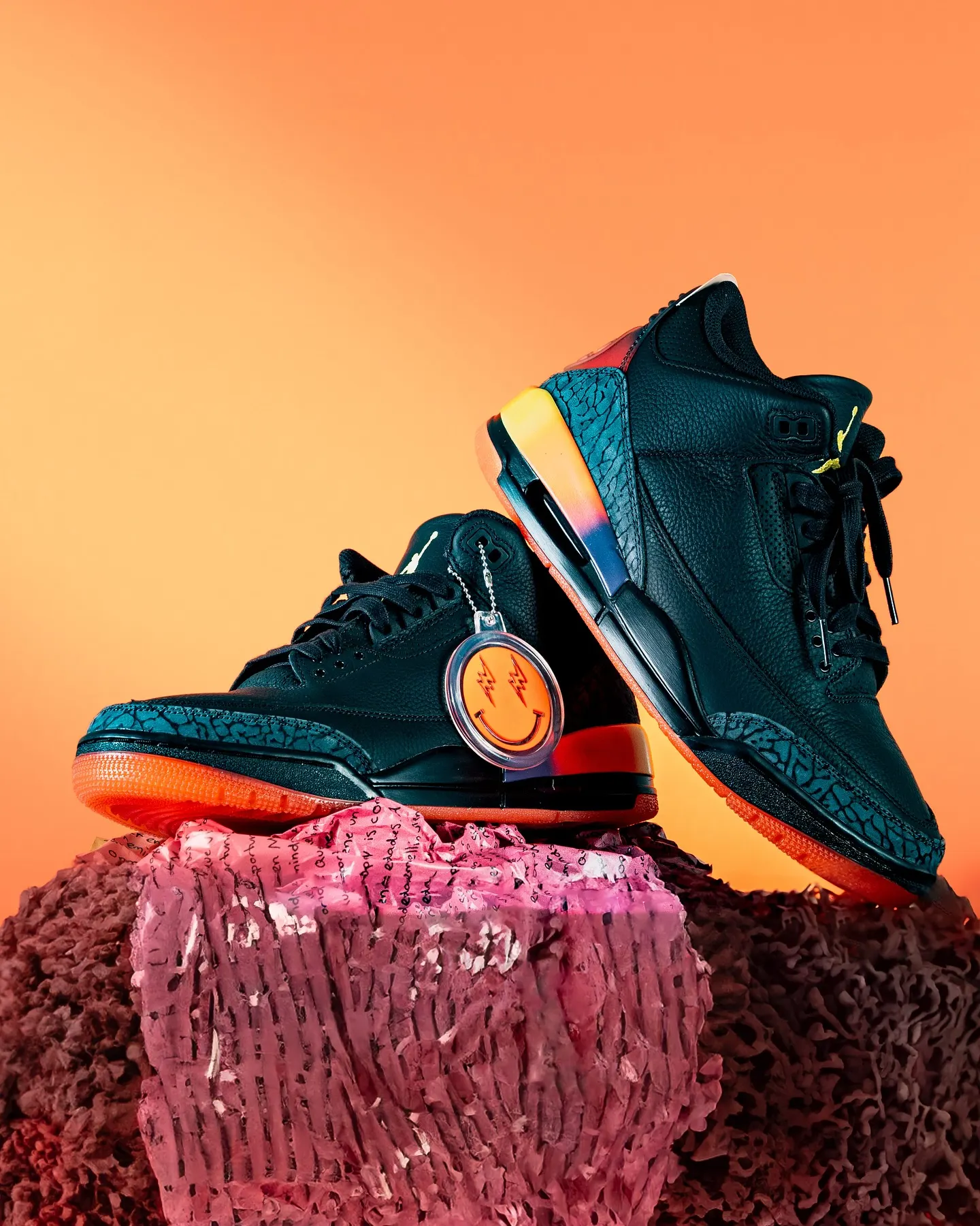 A teal high-top sneaker standing on a textured pink plinth against an orange background