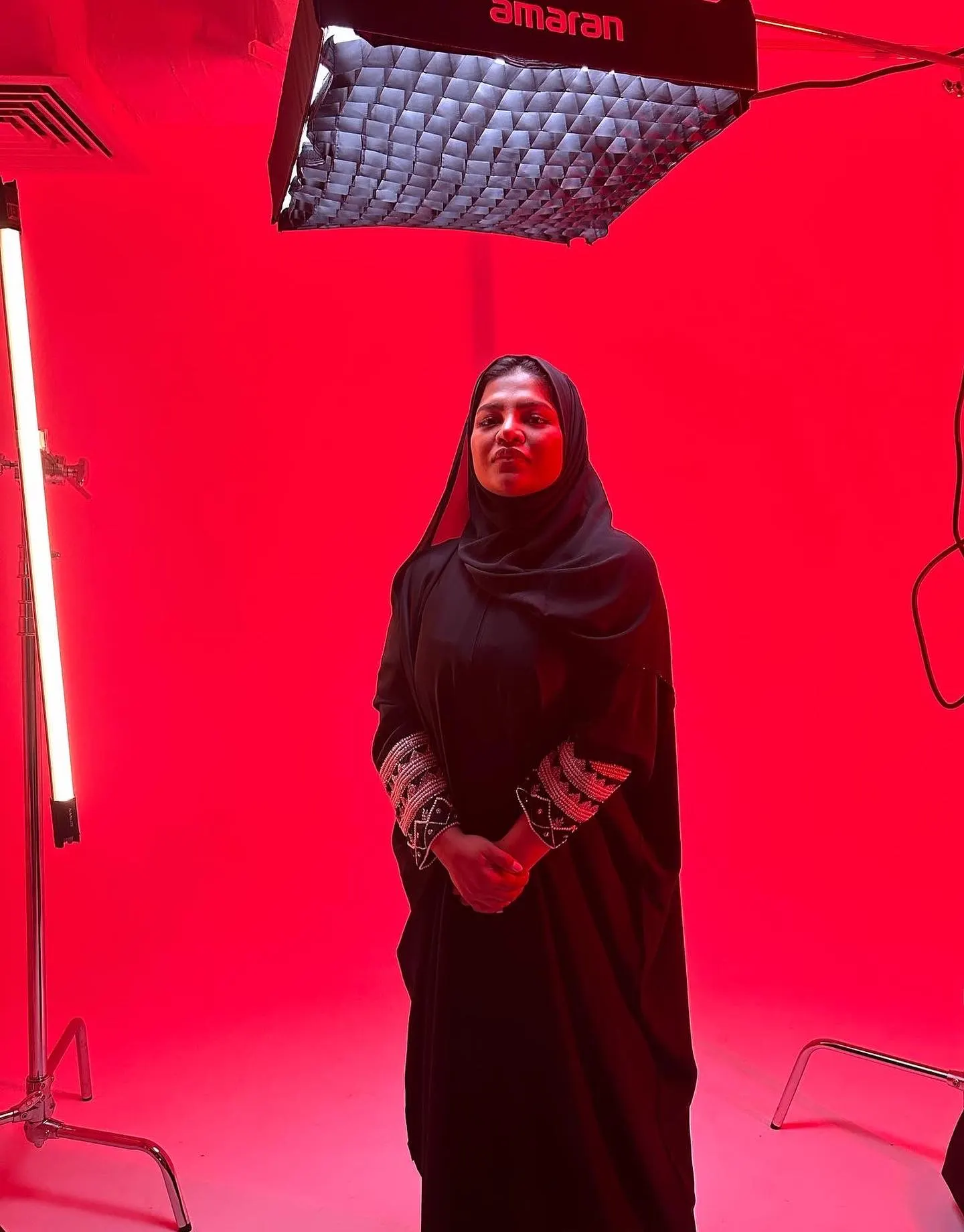 A studio portrait of a woman in black lit by a vertical tube light with a softbox overhead