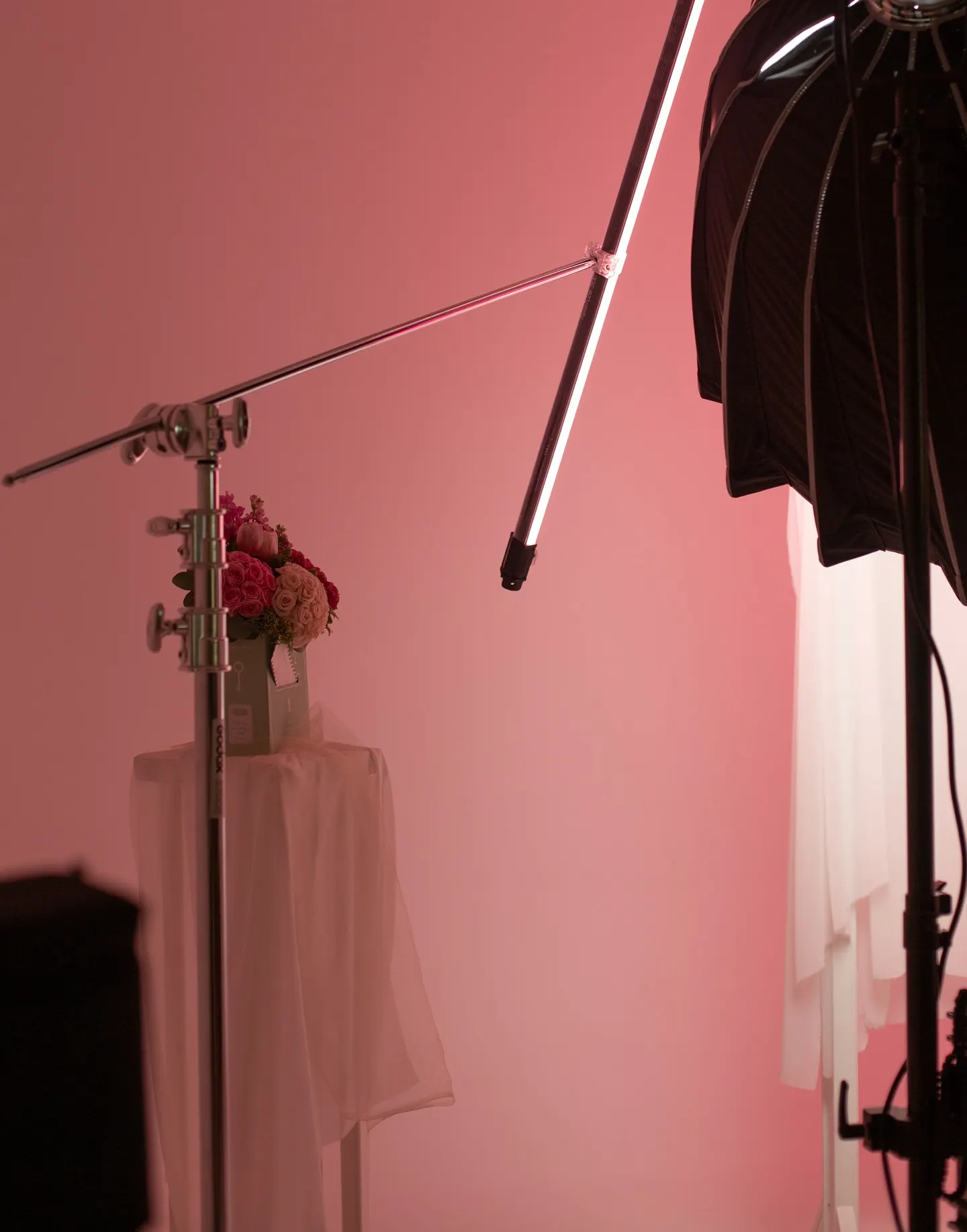 A boom arm and lighting positioned over a pink draped studio set