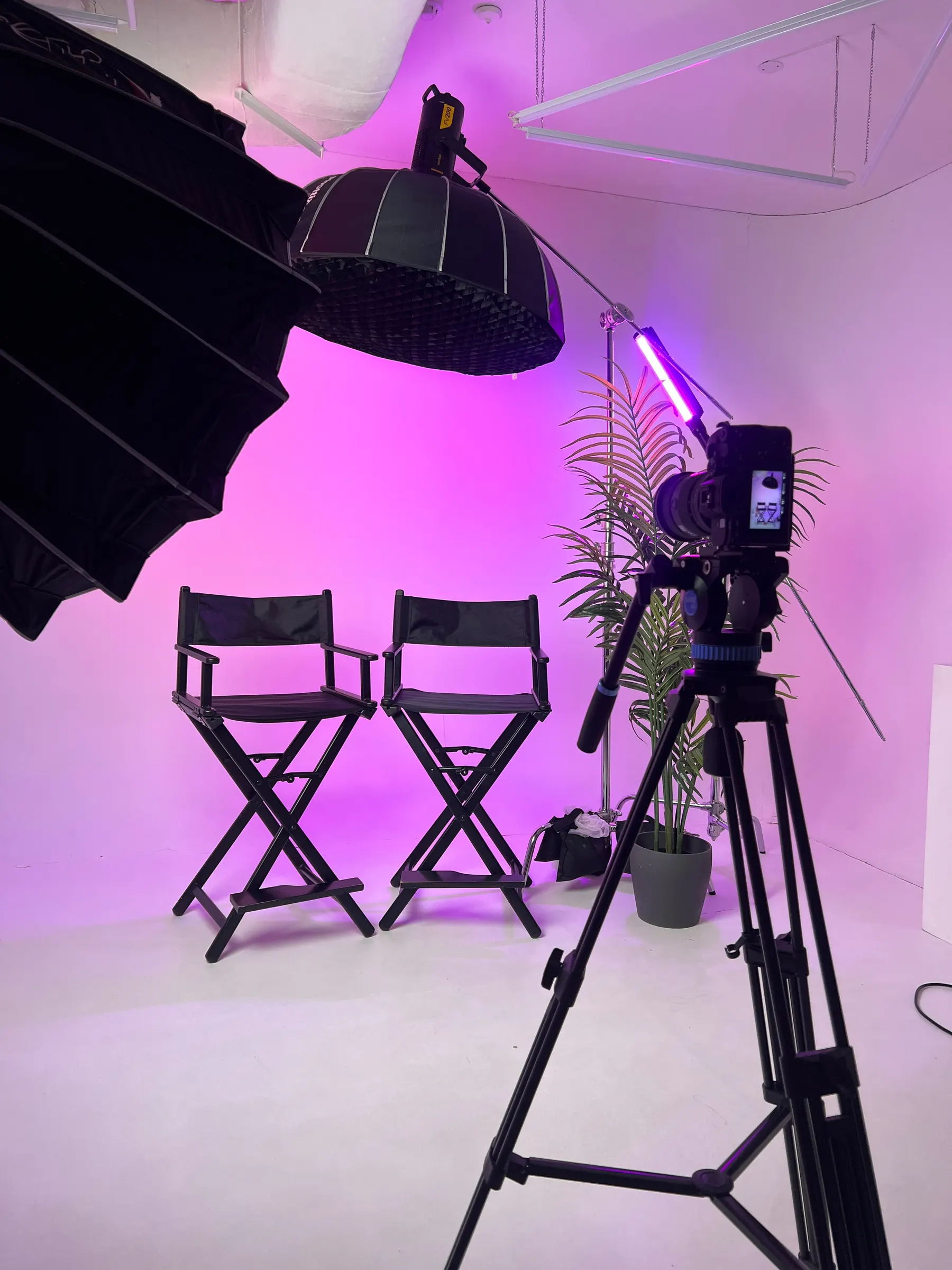 Interview set with director's chairs and a camera under magenta studio lighting