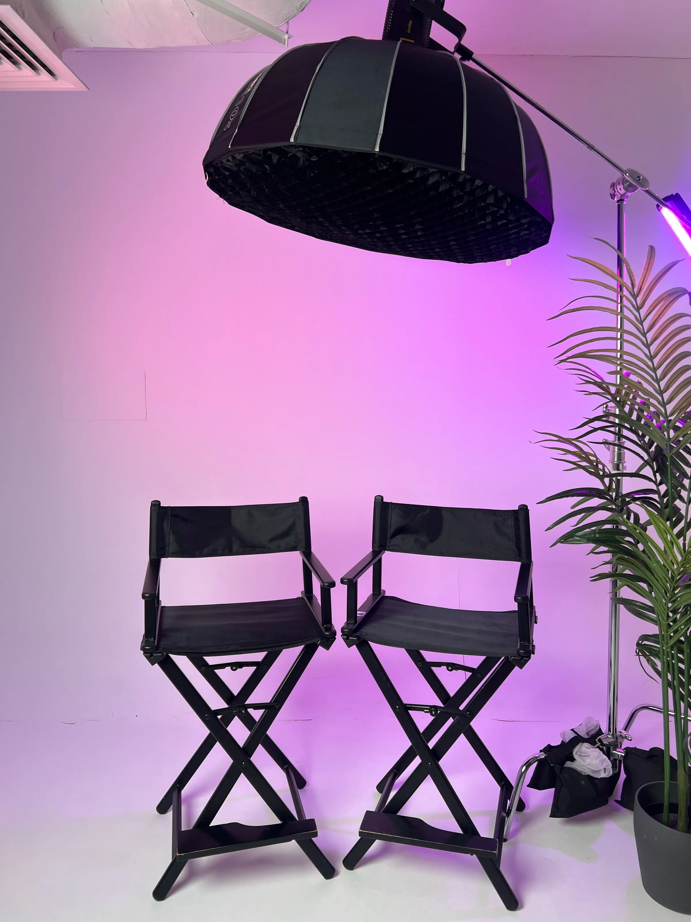 The Evo Media Pro studio in Abu Dhabi: two director's chairs, a large softbox and a plant under magenta light