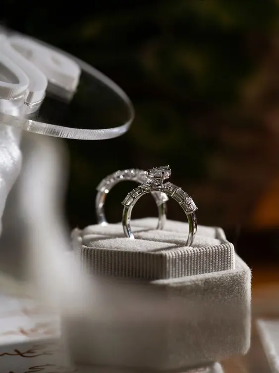 A diamond engagement ring and wedding band standing in a grey velvet ring box